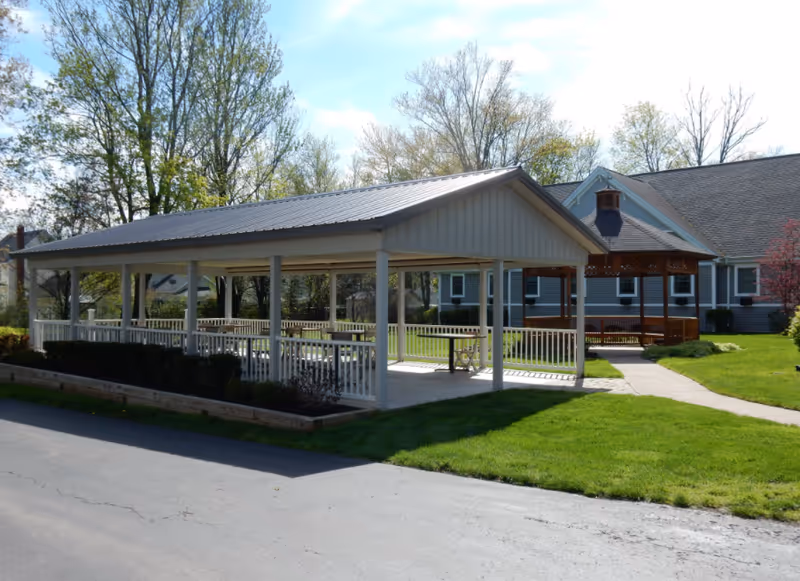 Exterior view of Whispering Oaks in Waverly showing a covered outdoor pavilion and green lawn.