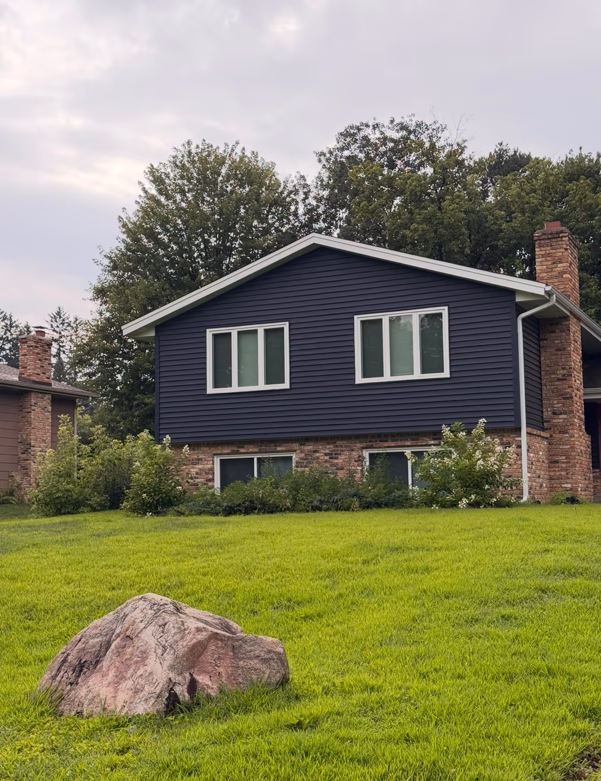 Blue two-story building with brick foundation and surrounding green lawn.