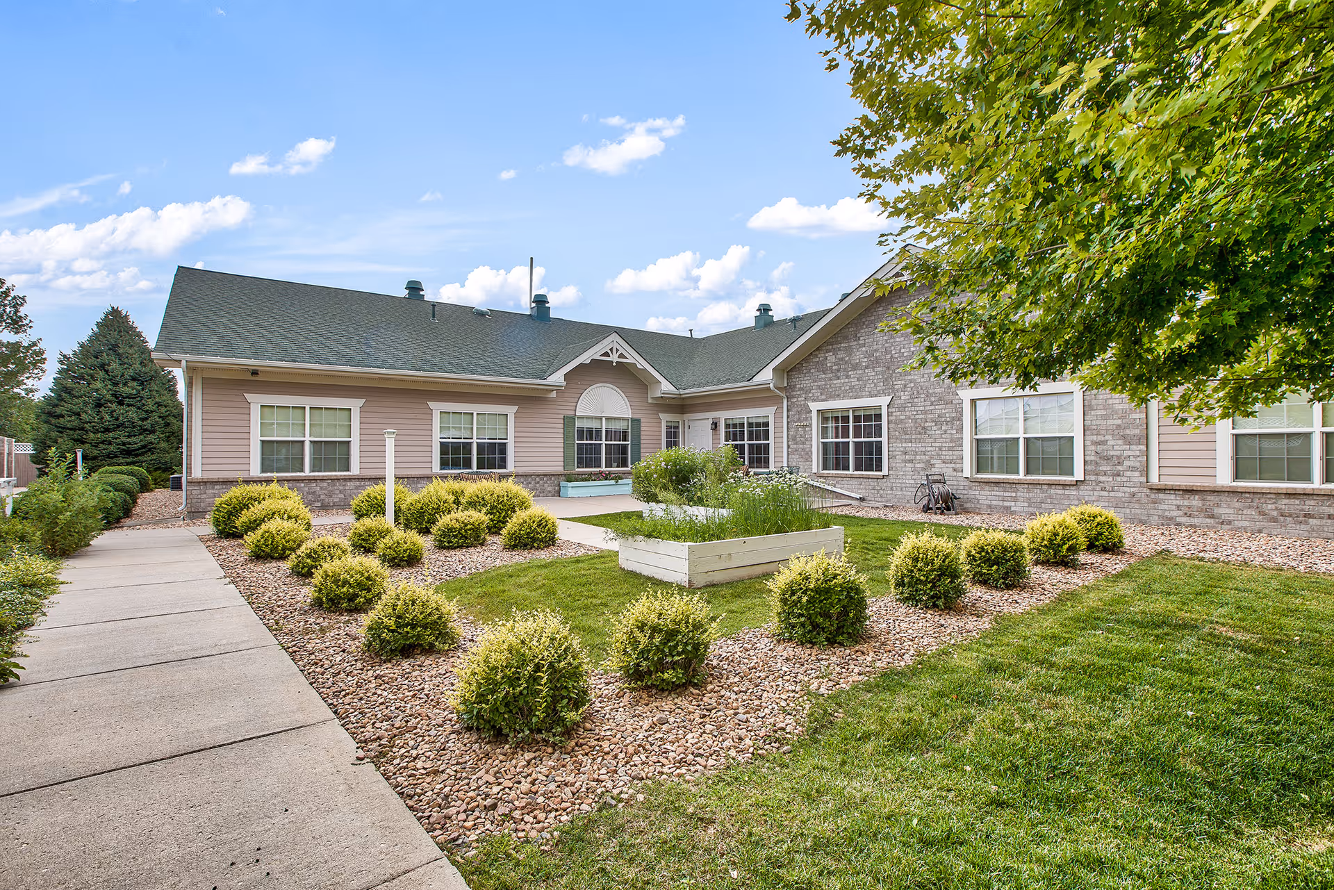 Front exterior view of Juniper Village at Louisville with landscaped shrubs and walkway.