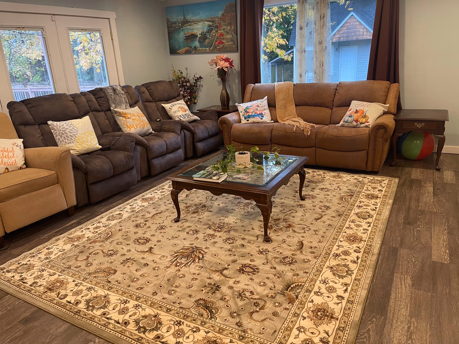 Cozy living room with brown sectional sofas, a glass coffee table, and decorative pillows on rug.