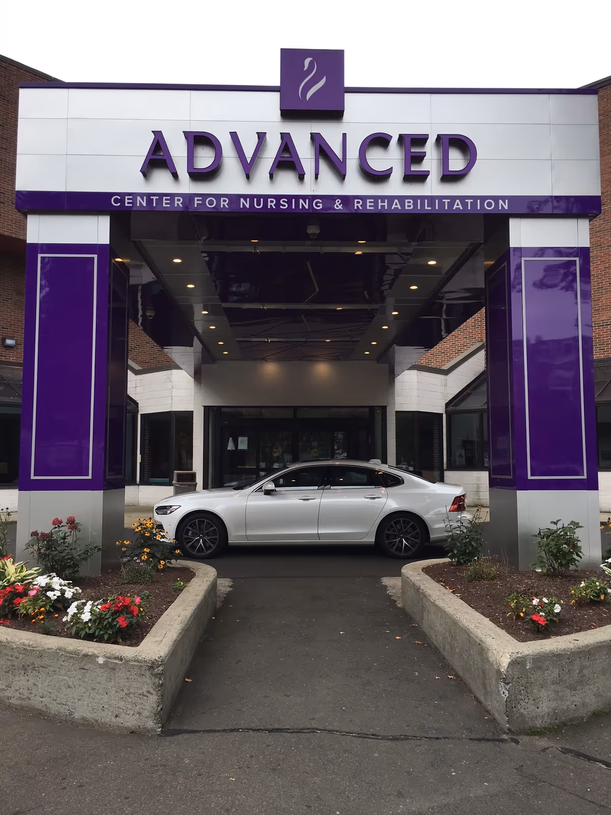 Front entrance of Advanced Center for Nursing & Rehabilitation with a white car parked outside.