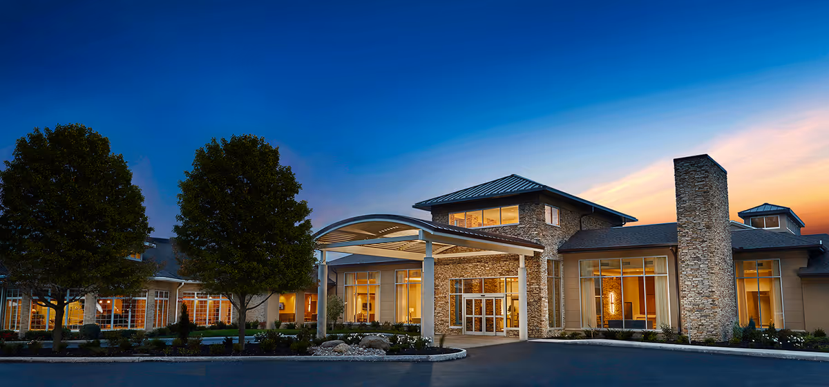 Exterior view of The Maplewood Nursing Home with stone facade and landscaped entrance at sunset.