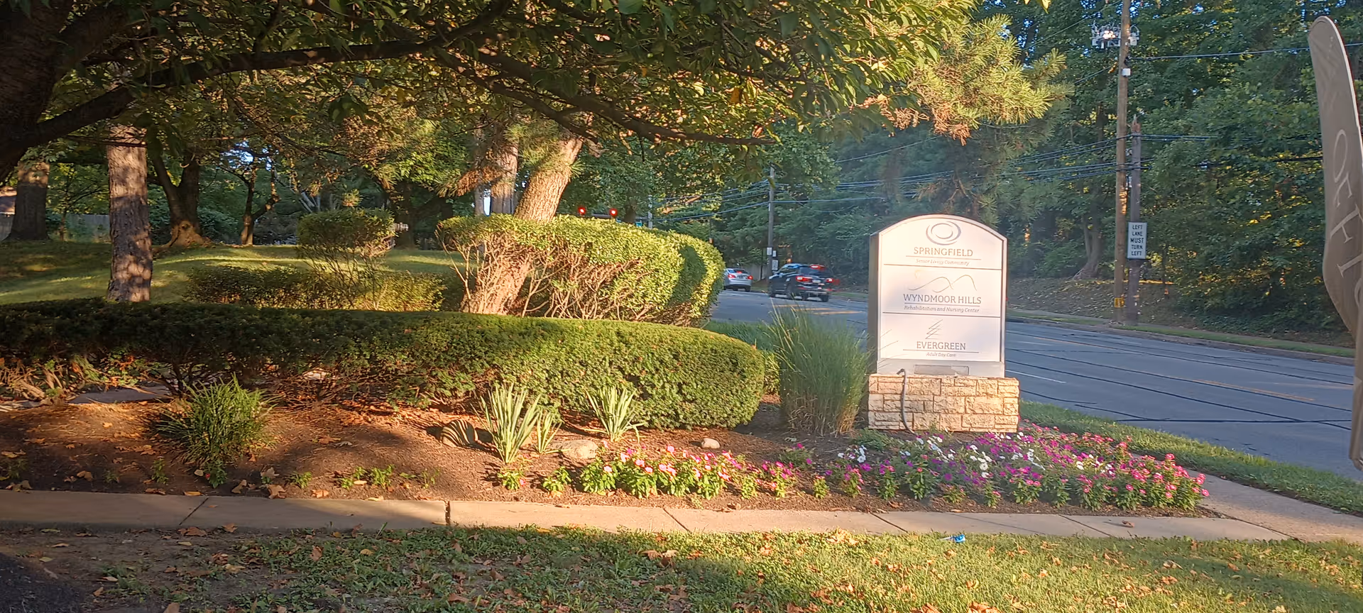 Well-maintained entrance landscape with flowering bed and a stone sign for Wyndmoor Hills.