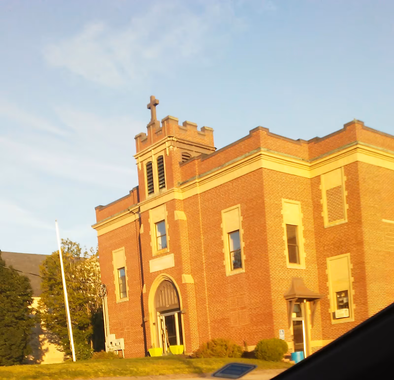 Red brick building with a cross on top and arched entrance at the front.