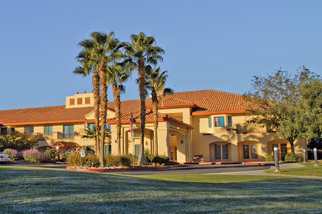 Exterior view of The Havens at Antelope Valley with a beige building and palm trees.