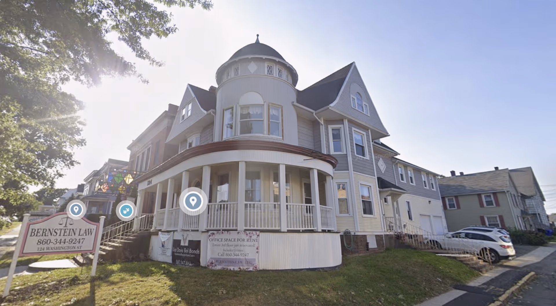 Victorian-style multi-story house with a wraparound porch on a residential street
