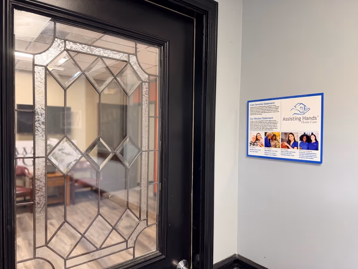 Interior doorway with decorative glass panel and a wall-mounted Assisting Hands information poster.
