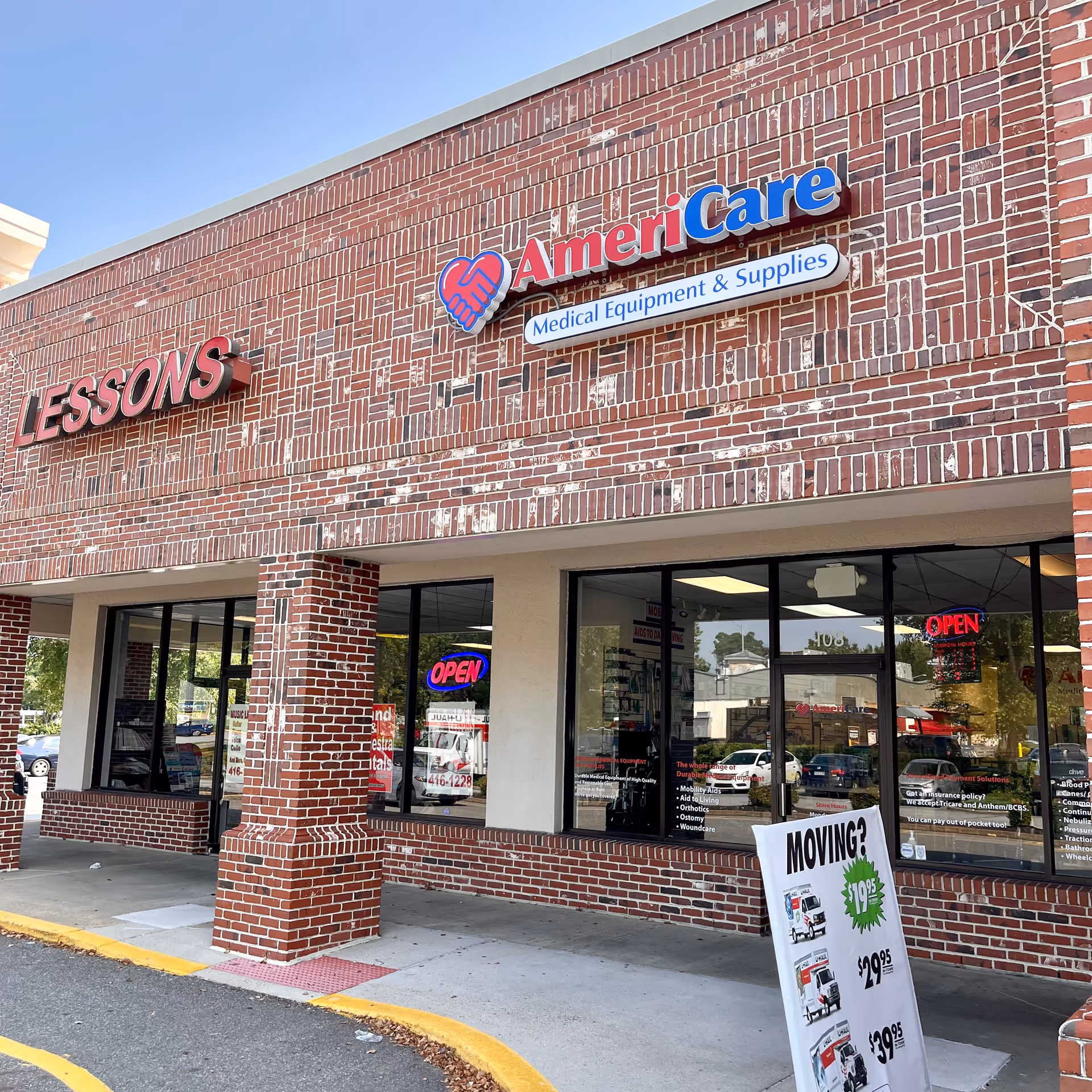 Brick storefront with AmeriCare Medical Equipment & Supplies sign and open neon signs.