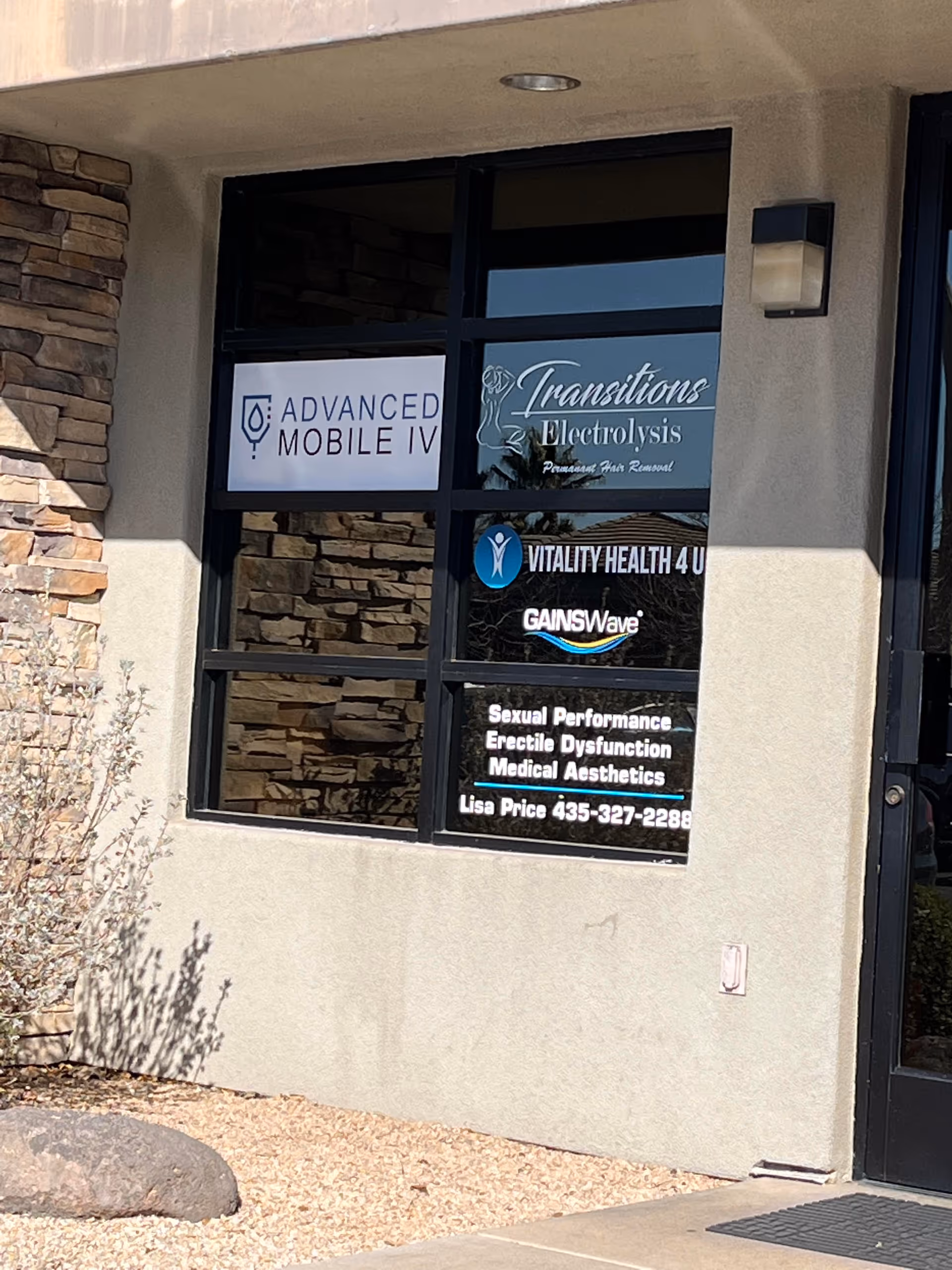 Exterior building front with a large window displaying Advanced Mobile IV signs.