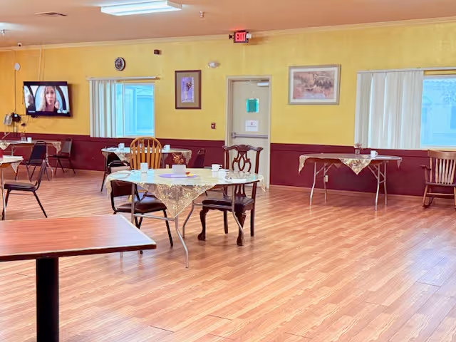 A large, well-lit dining area with round tables and chairs in a senior facility.