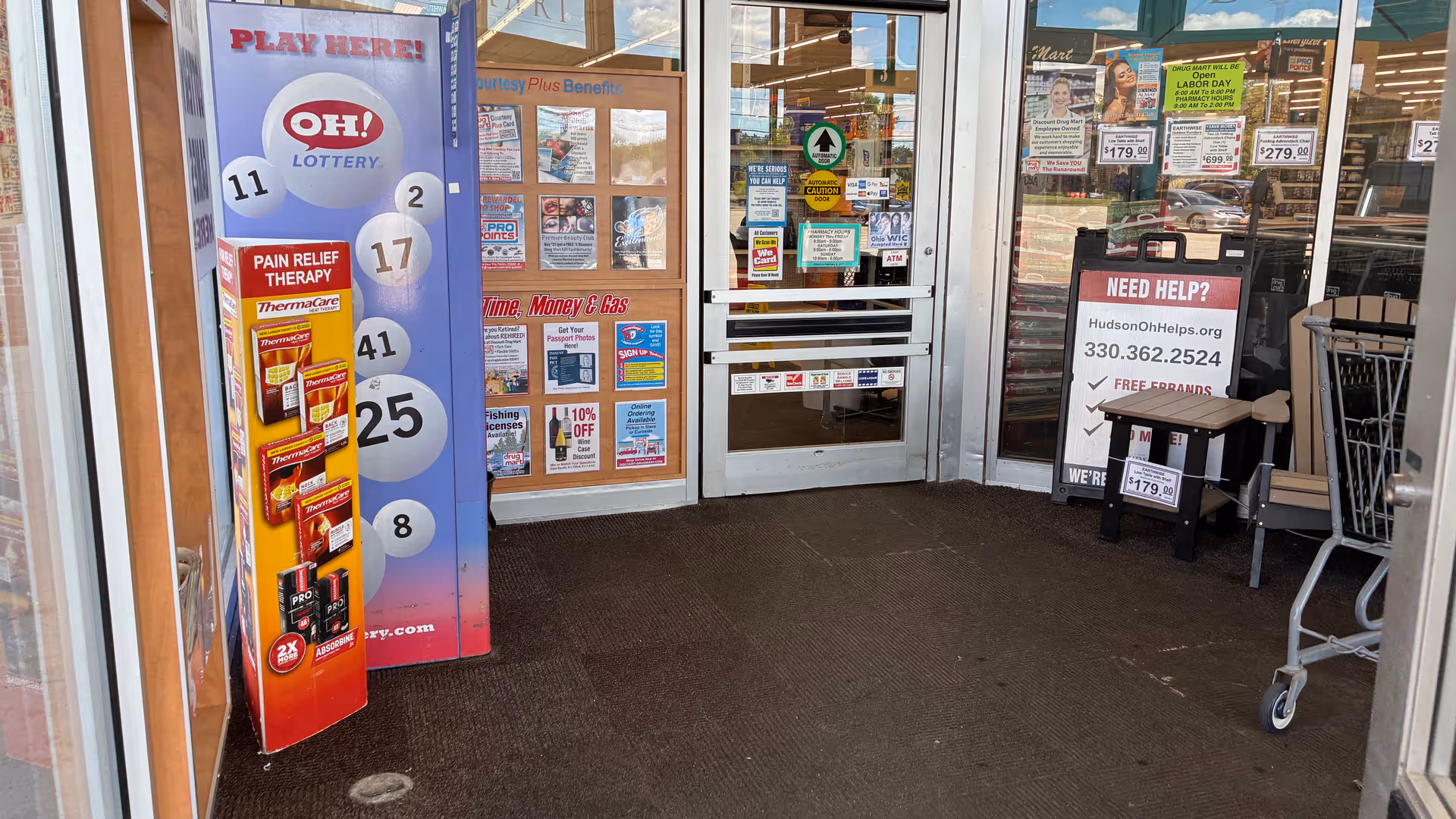 Discount Drug Mart storefront entrance with lottery vending machine and shopping carts outside