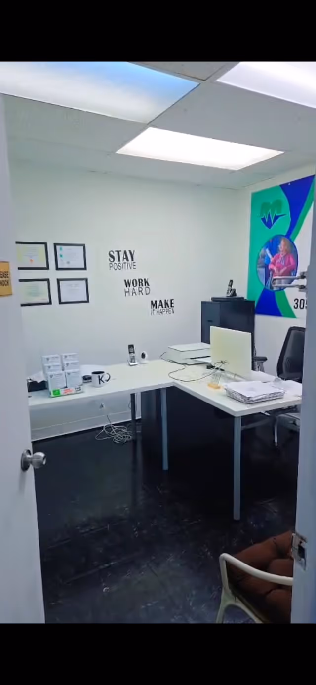 Small staff office with desk, computer, documents, and motivational wall quotes.