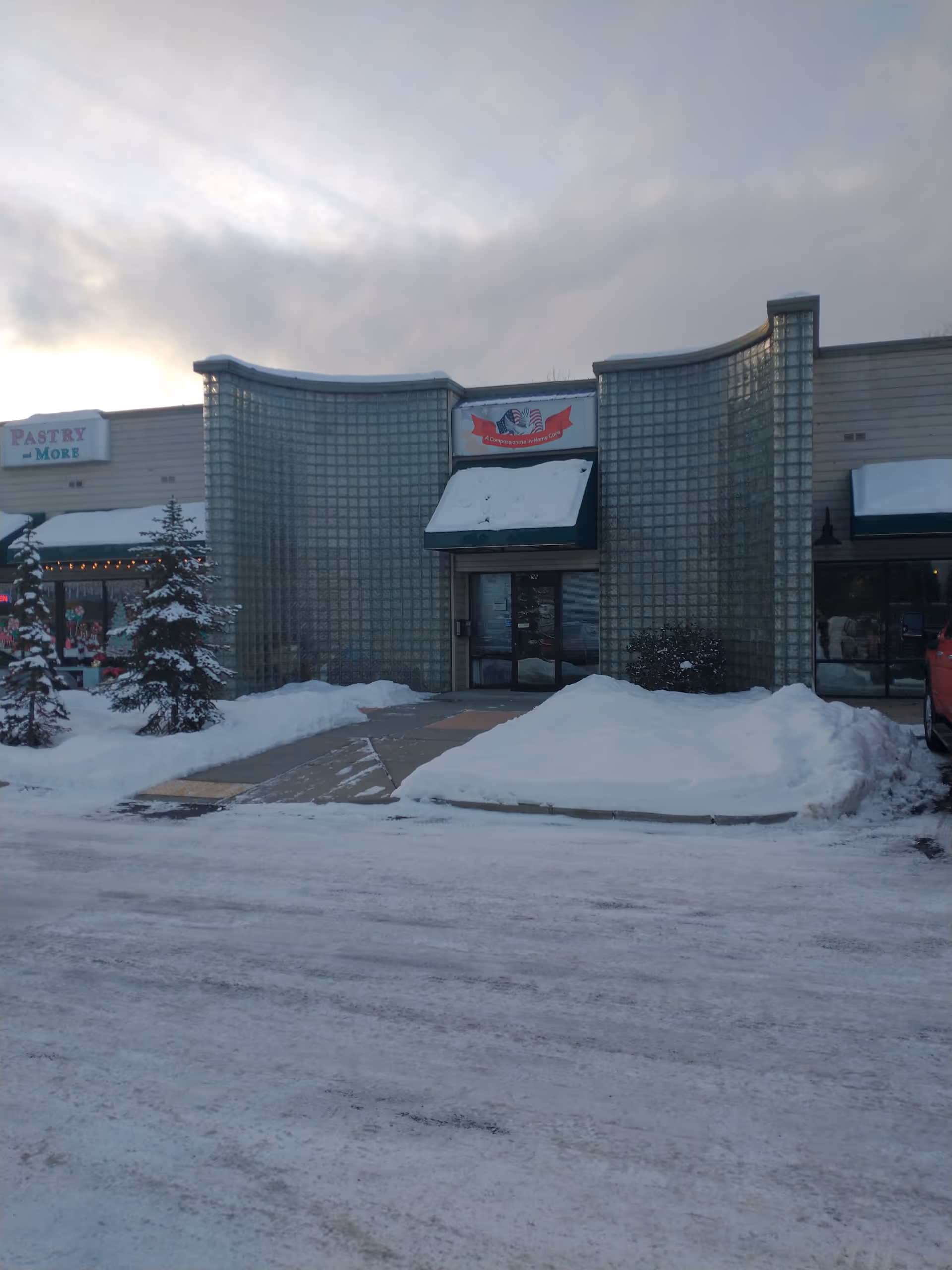 Snowy exterior of a storefront building with glass-block facade and a central entrance.