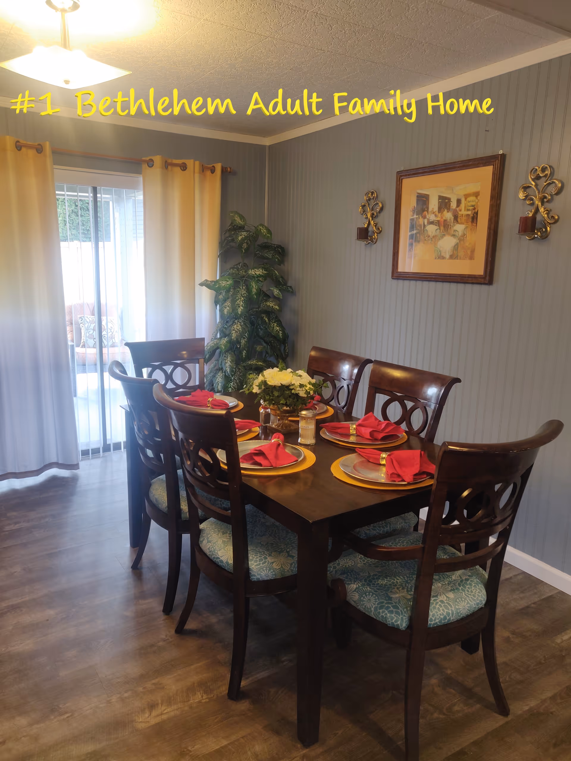 A dining room with a wooden table set for six and red napkins.
