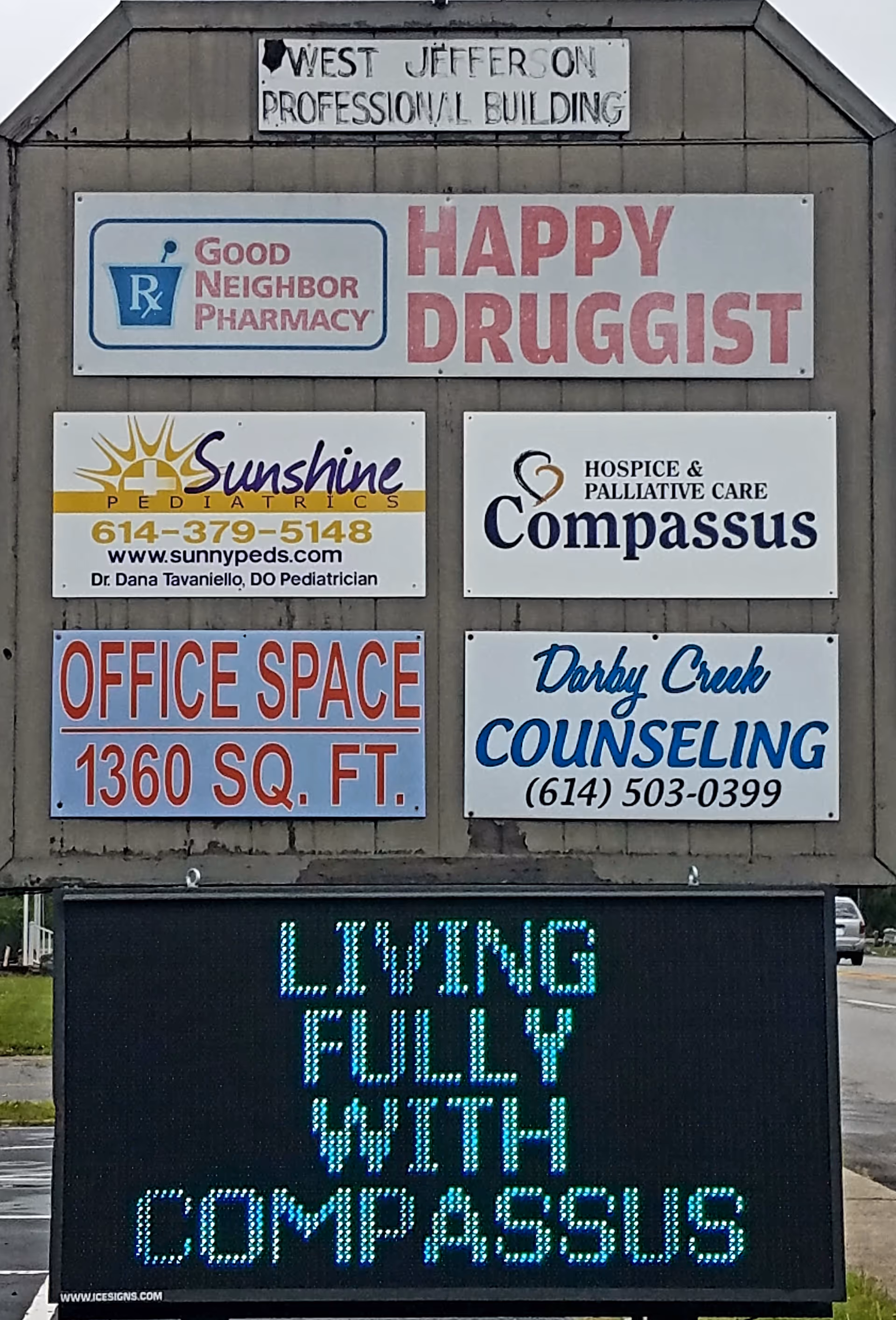 Outdoor building signboard featuring Compassus and other business signs on a wooden structure