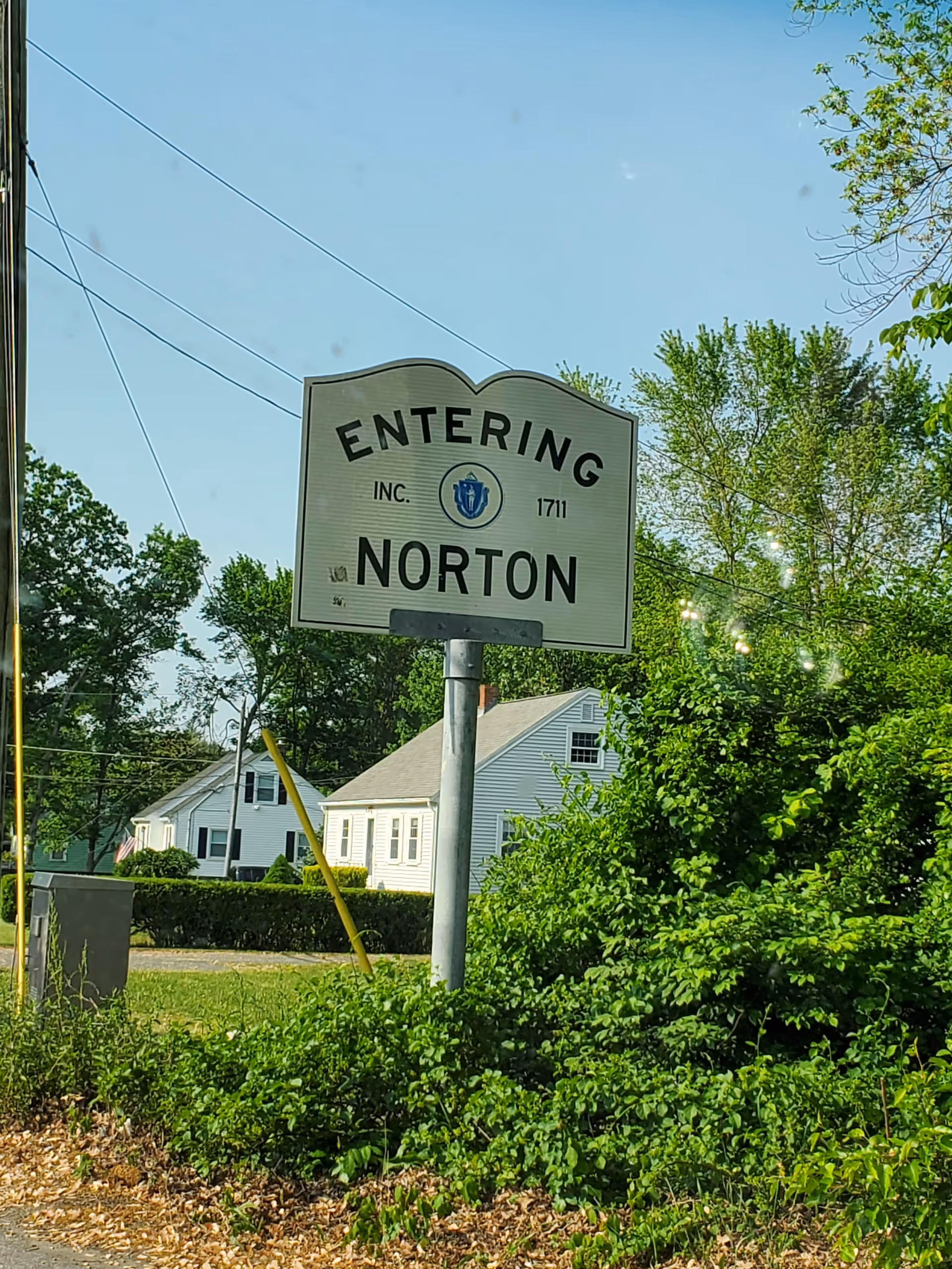 A street sign reads 'Entering Norton' with green trees and white houses in the background.