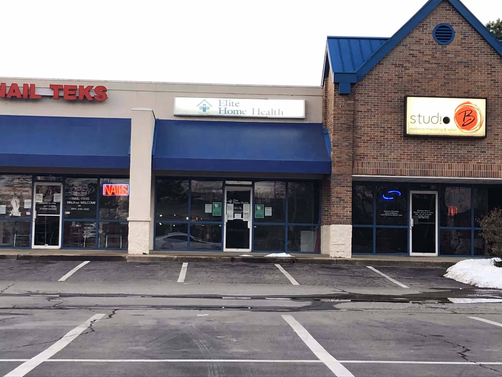 Exterior of a strip mall with Elite Home Health storefront sign and other businesses.