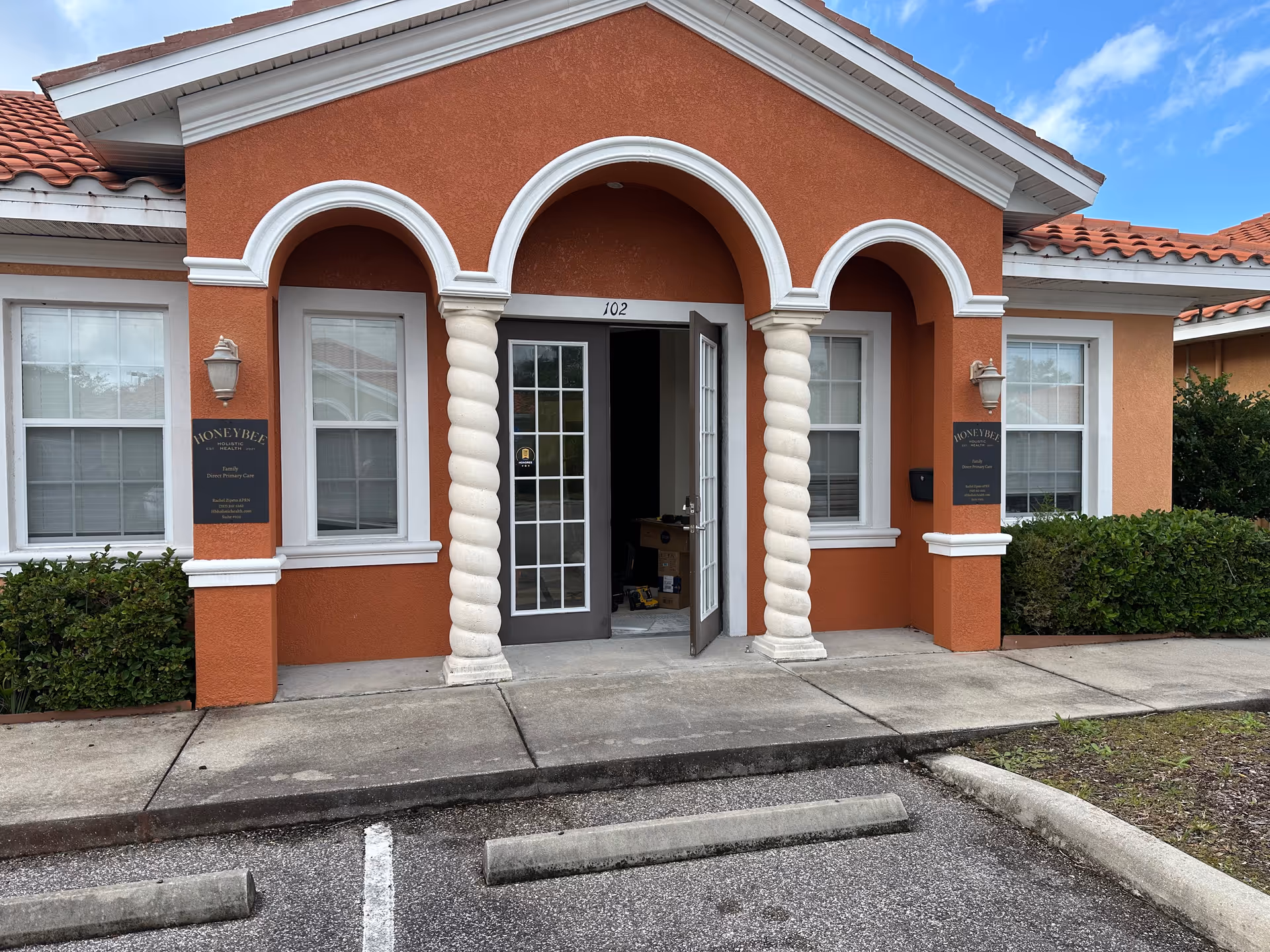 Orange stucco building entrance with arched openings and twisted columns, no people visible.