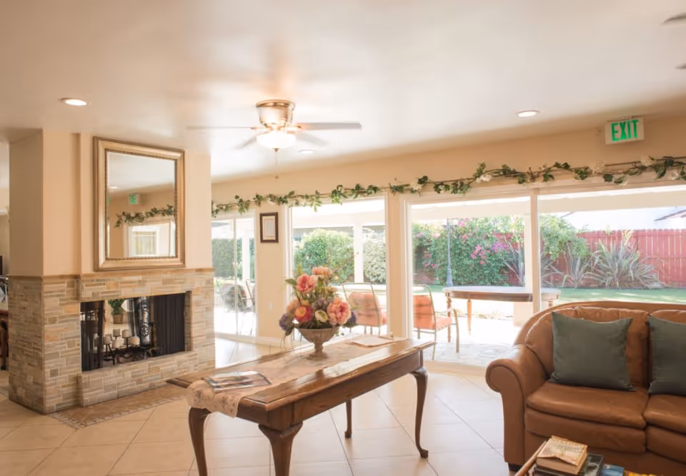 Bright living room with fireplace, sofa, wooden table, and large glass doors to patio.