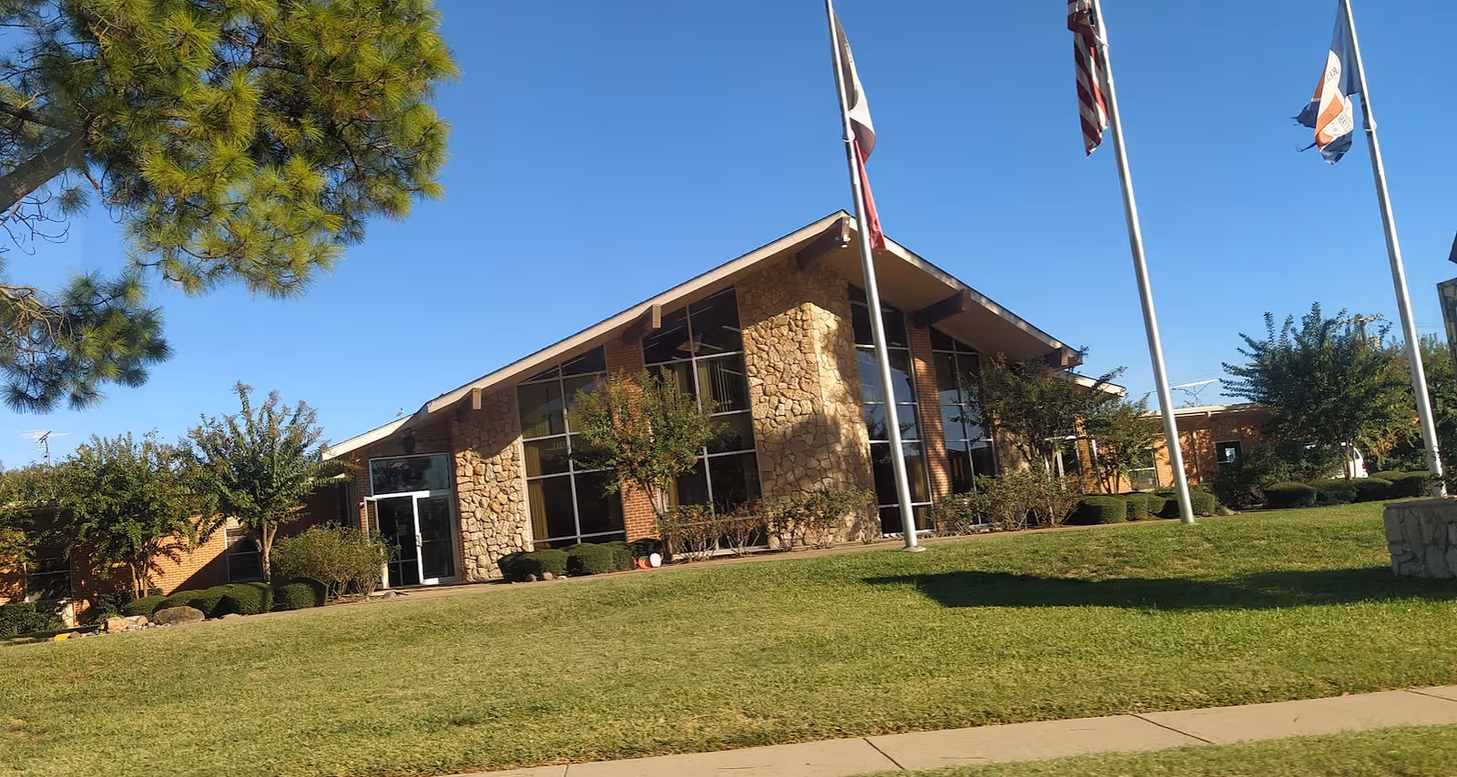 Front exterior of Town Hall Estates Nursing and Rehab building with flagpoles and lawn