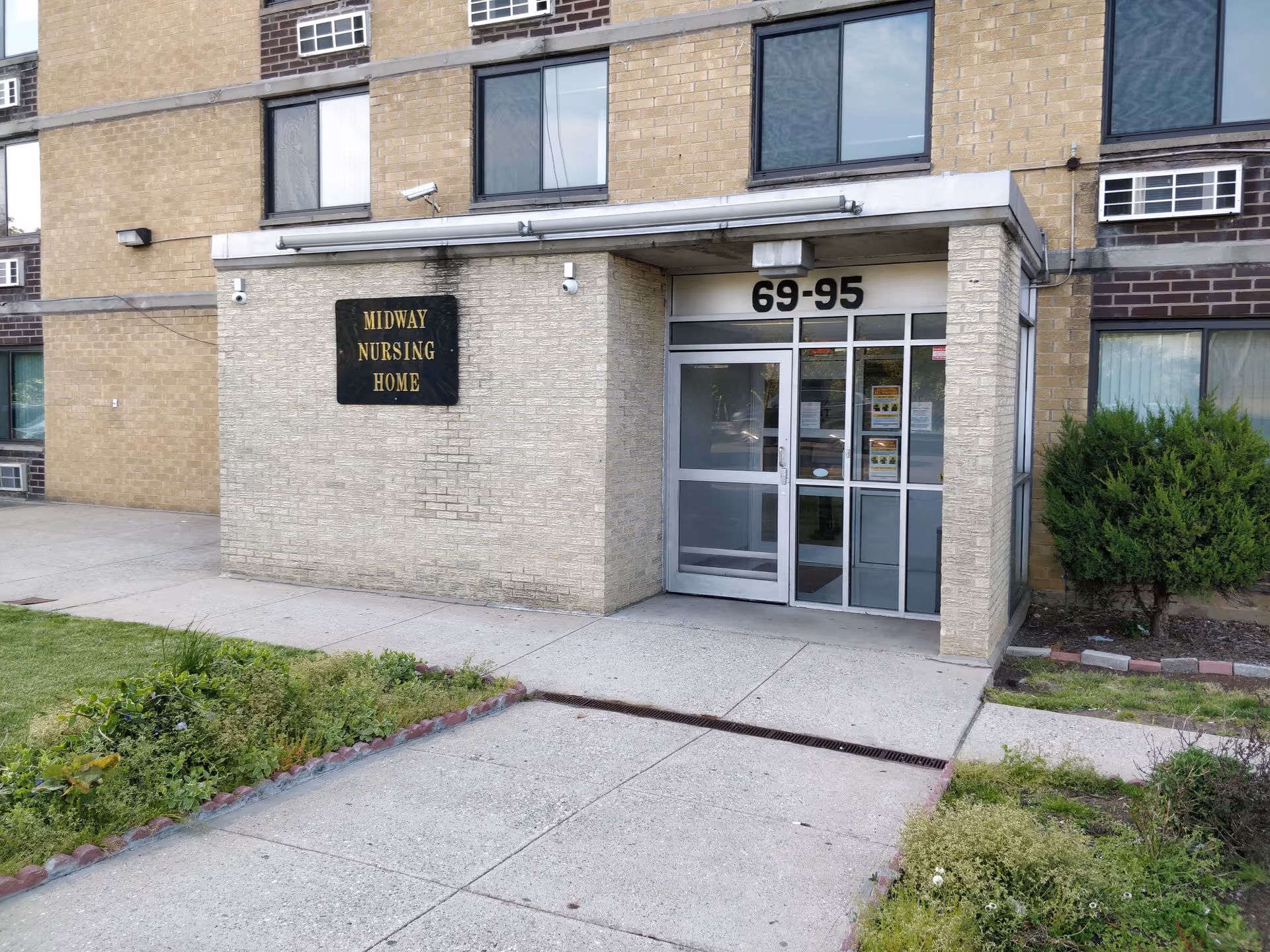 Exterior view of a nursing home entrance with glass doors and a sign