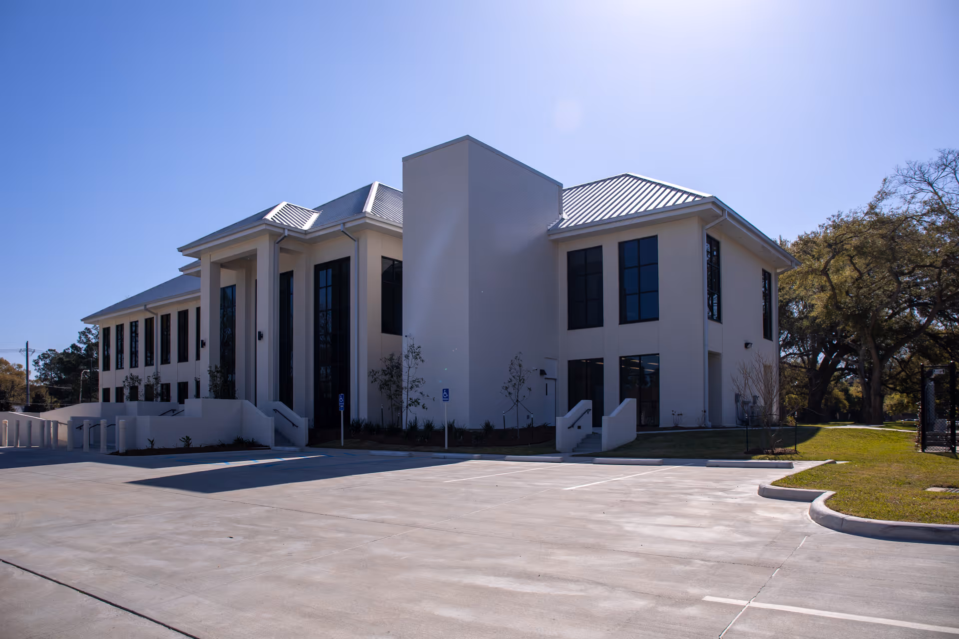 White modern senior living facility building with tall windows and a spacious parking lot.