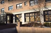 Exterior of Long Island Care Center: brick building, glass entrance, curved canopy, and planters.