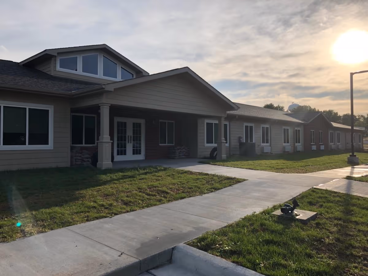 Exterior view of Pawnee City Assisted Living building with entrance, walkway, and surrounding lawn.