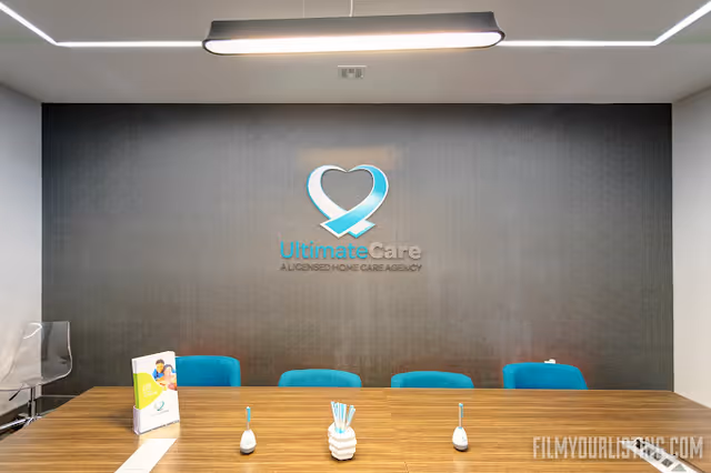 A conference room with blue chairs and the UltimateCare logo on a dark wall.