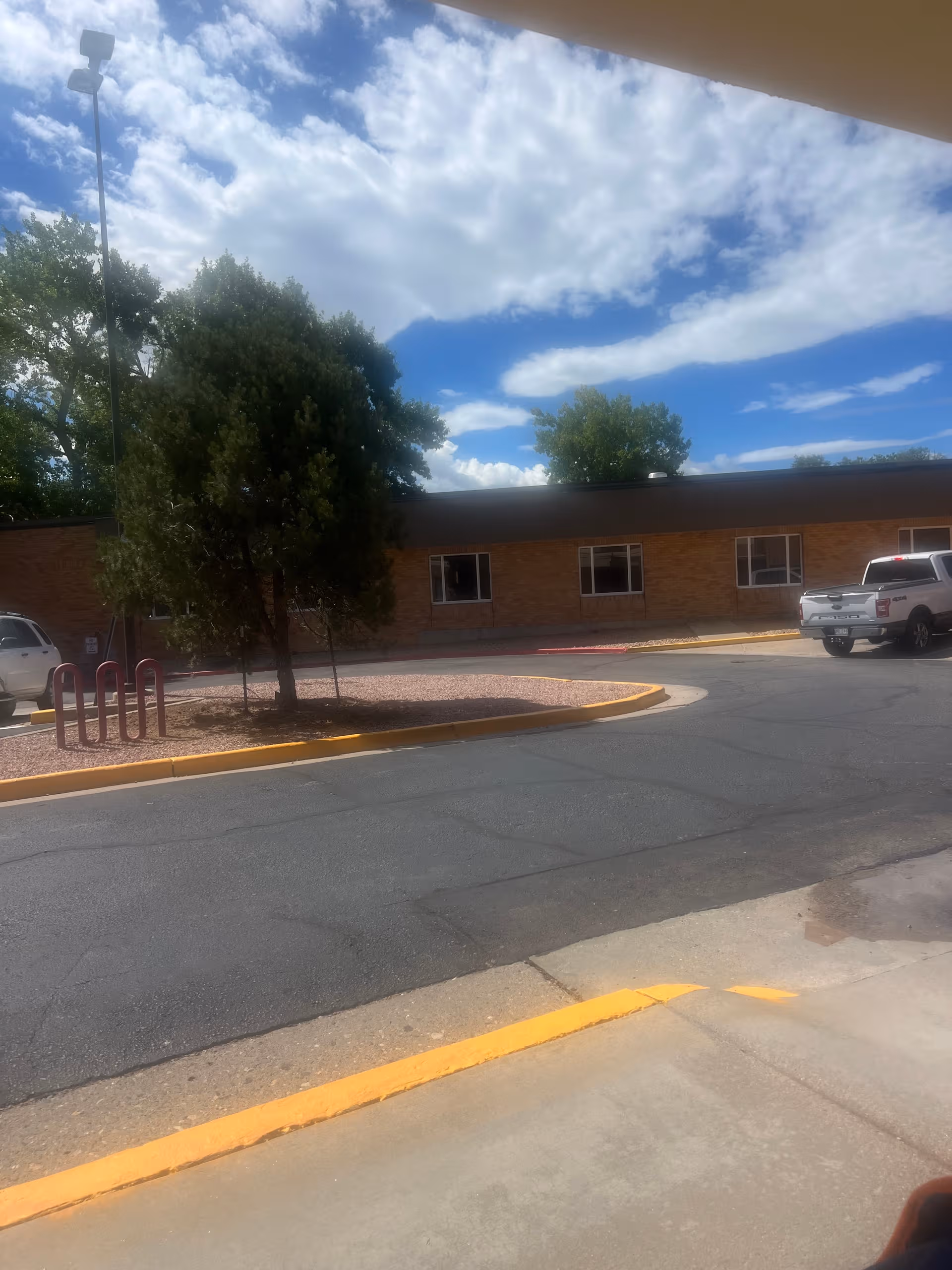 Exterior view of Progressive Care Center with brick building, trees, and a parking lot.