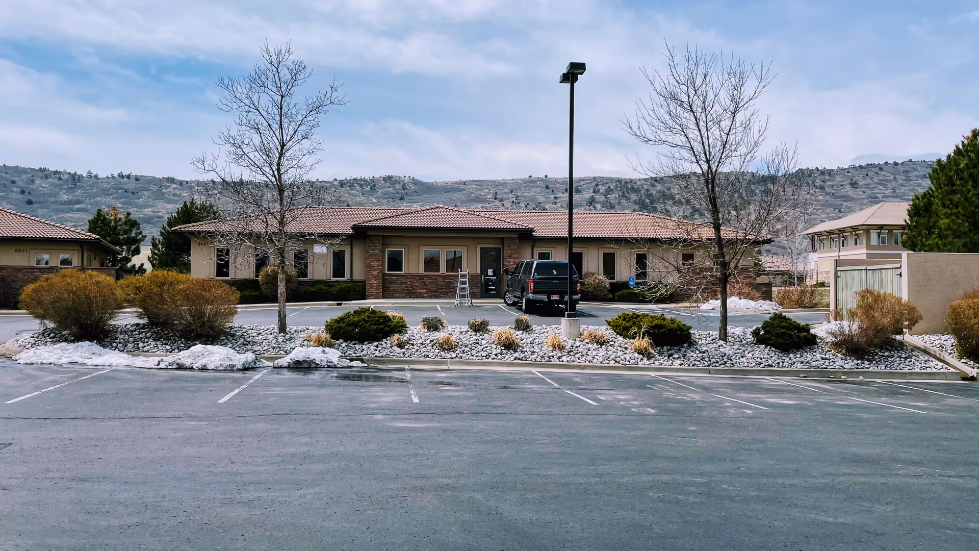 Front view of a single-story senior living facility with a parking lot and landscaping.