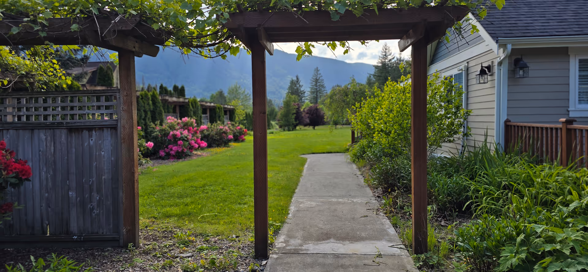 Exterior garden path toward a lawn with flowering shrubs beside Snoqualmie Valley Senior Care home.