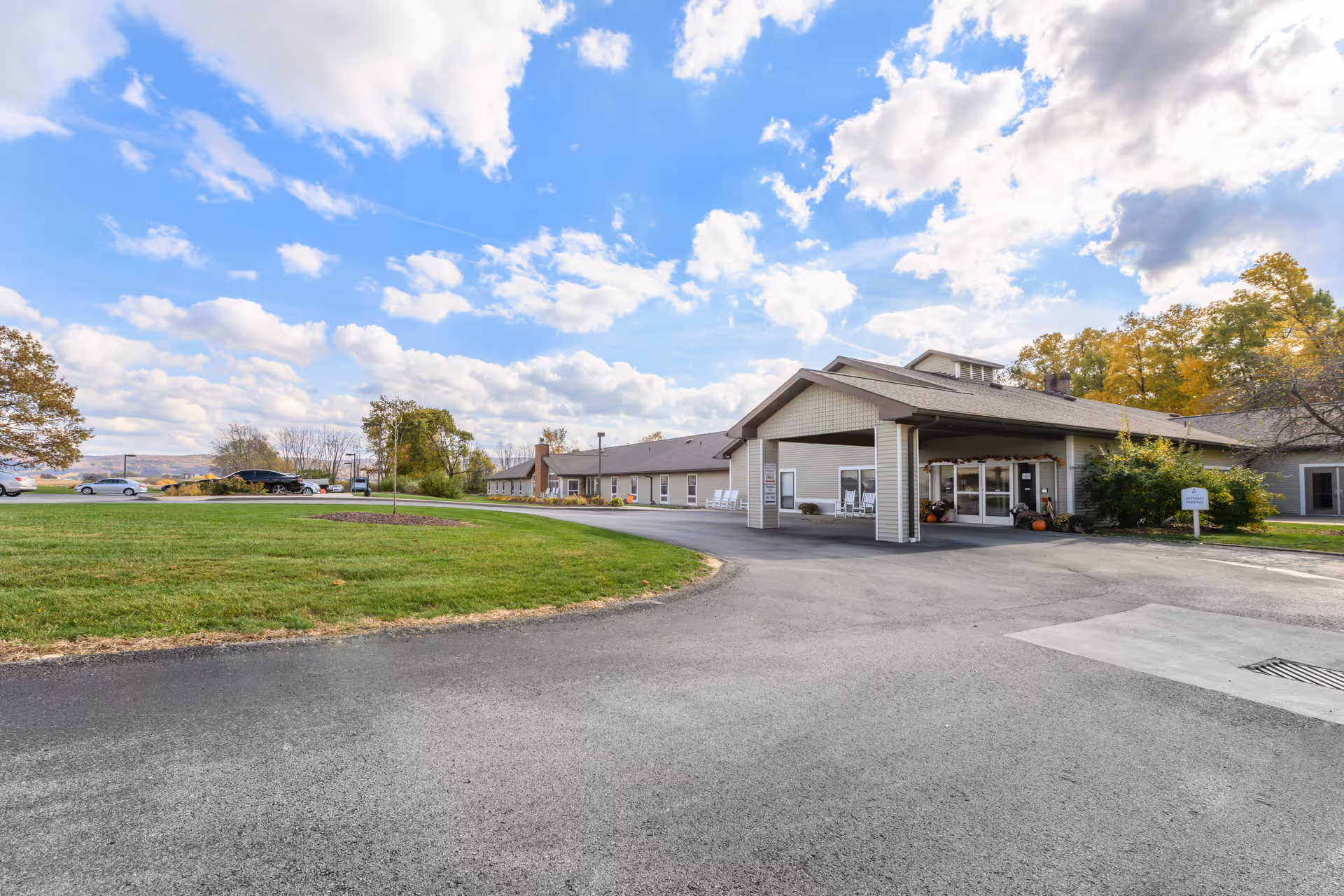 Sunny exterior view of Brookdale Latrobe with a curved driveway and building entrance