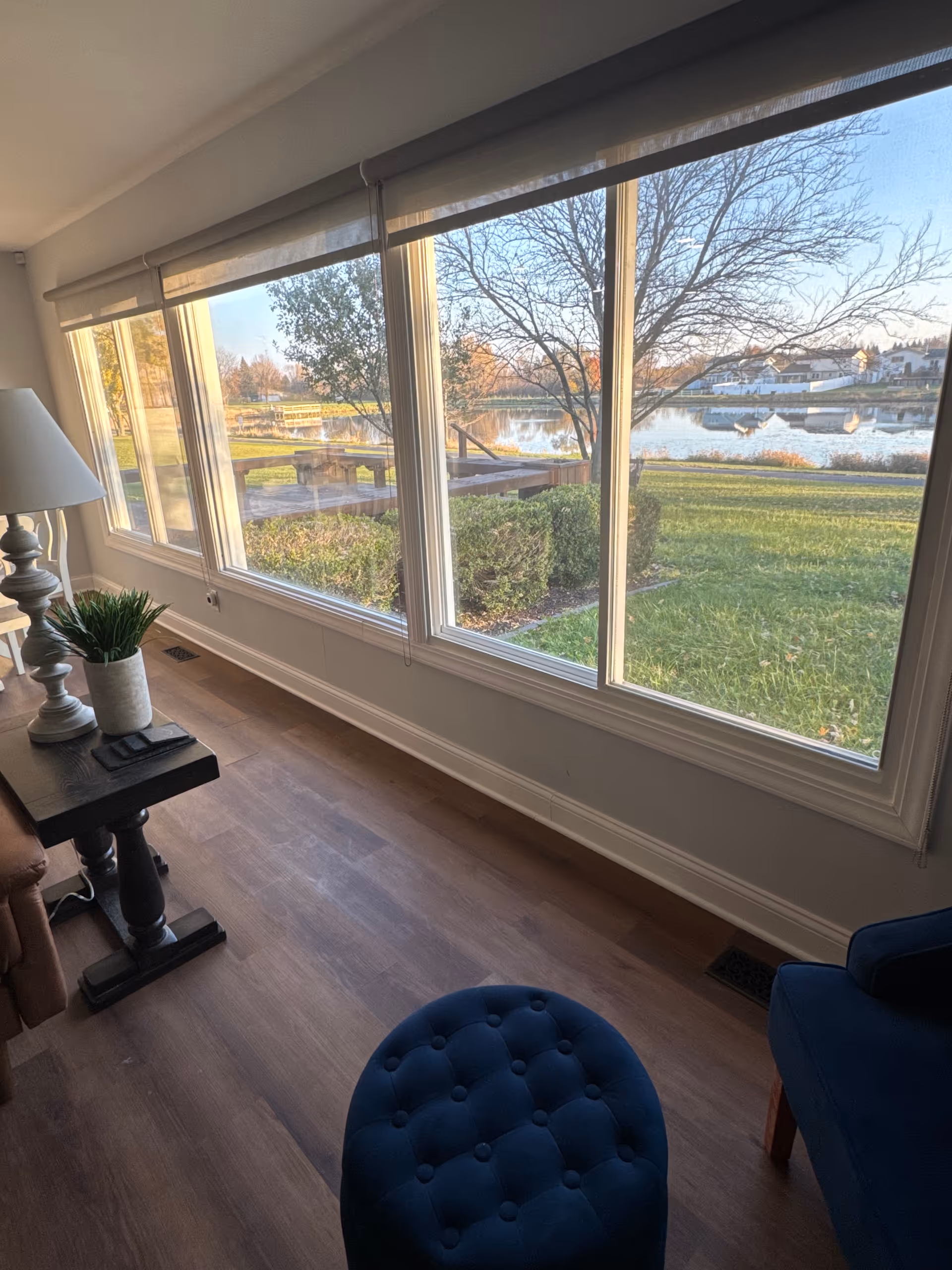 Interior living area with large windows overlooking a lake and greenery.