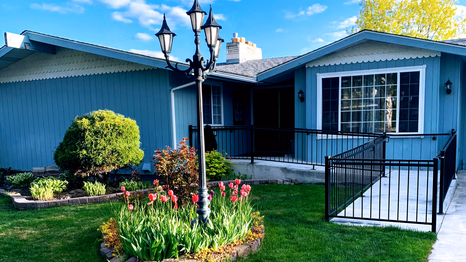Blue single-story facility exterior with ramp, railing, and tulip garden.