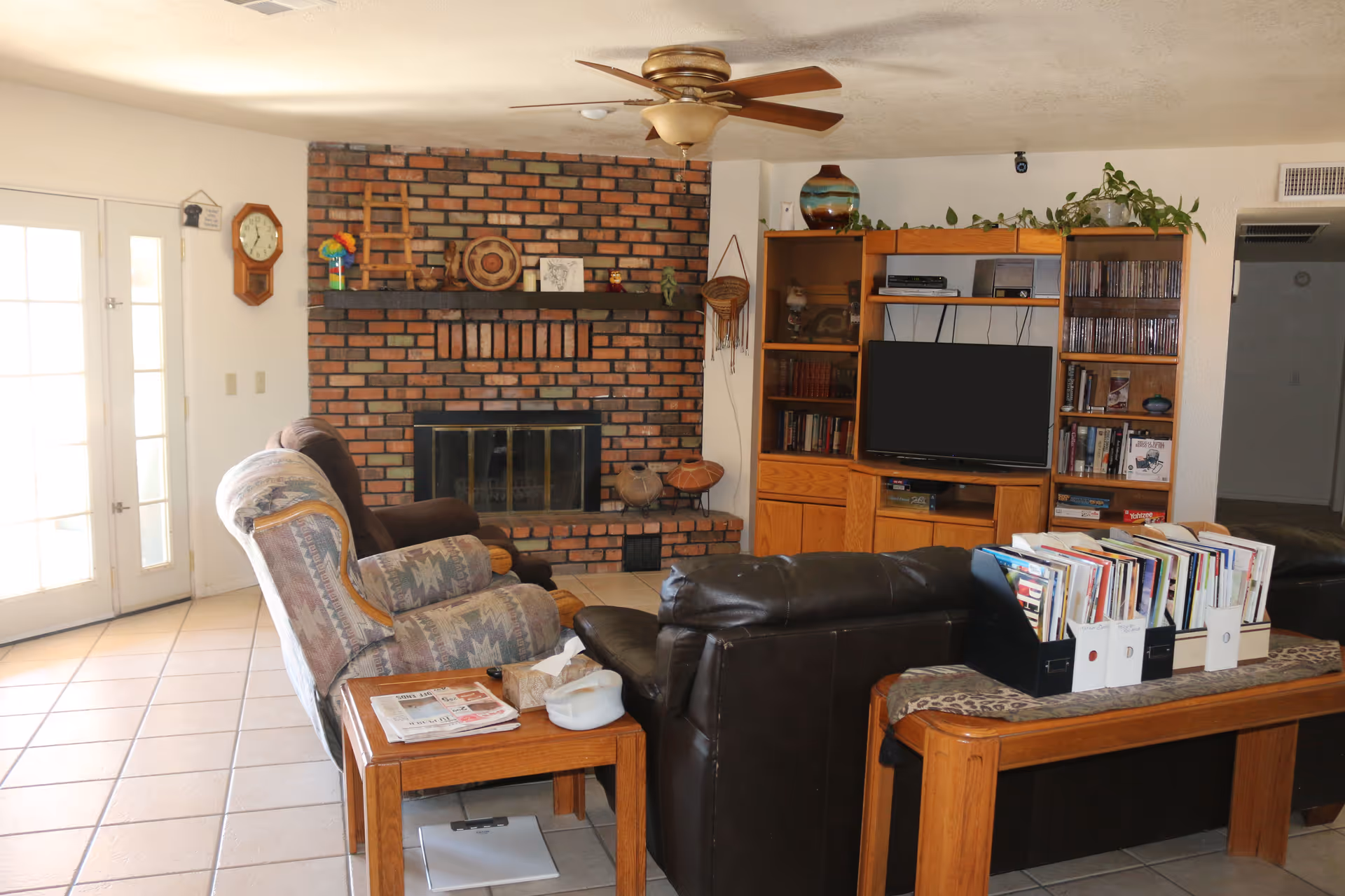Cozy living room with brick fireplace, leather seating, and a built-in TV bookshelf.