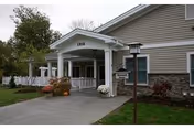 Exterior view of ThriveCare Assisted Living entrance with covered porch and plants.