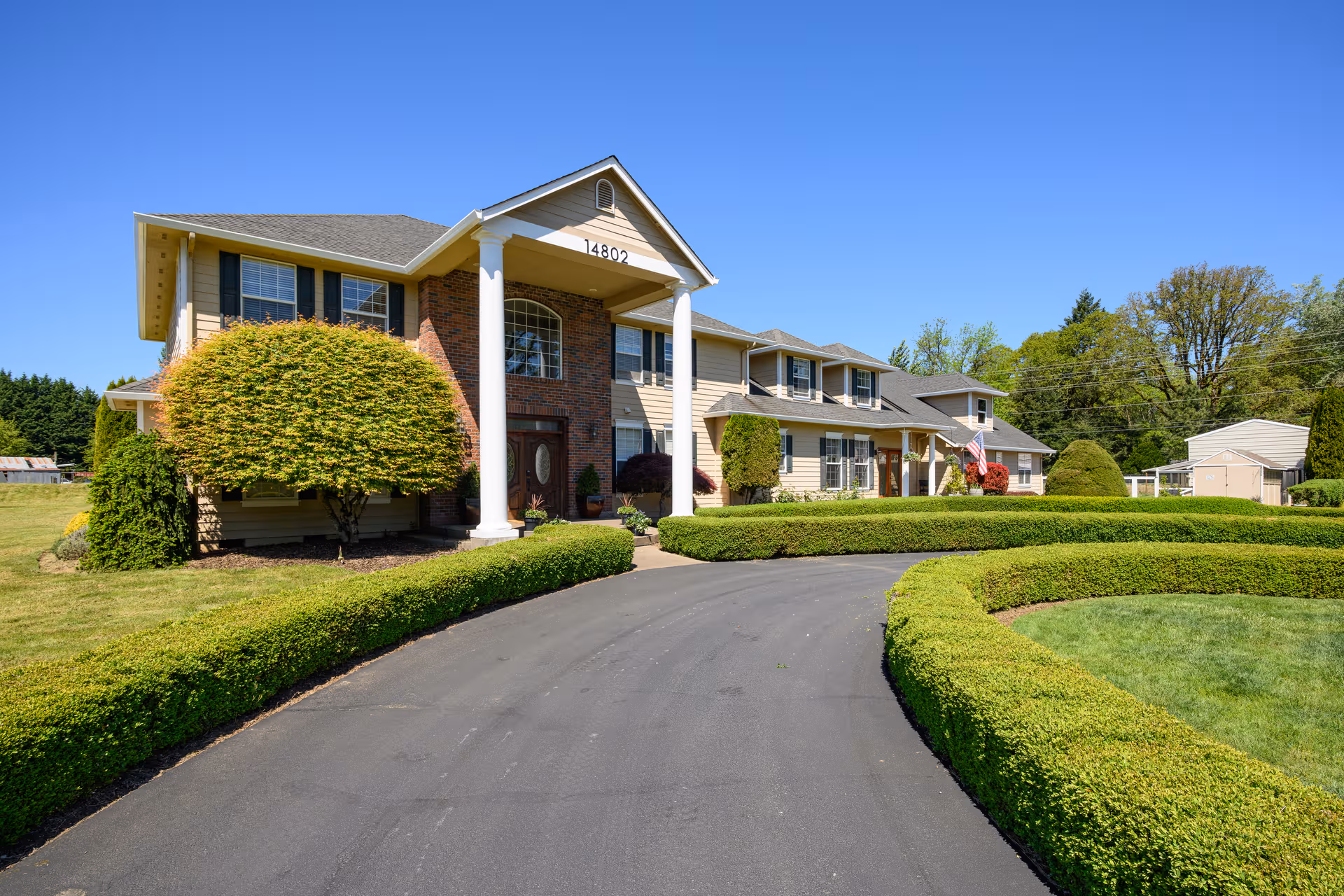 Front view of A Place to Call Home LLC senior living facility with trimmed hedges.