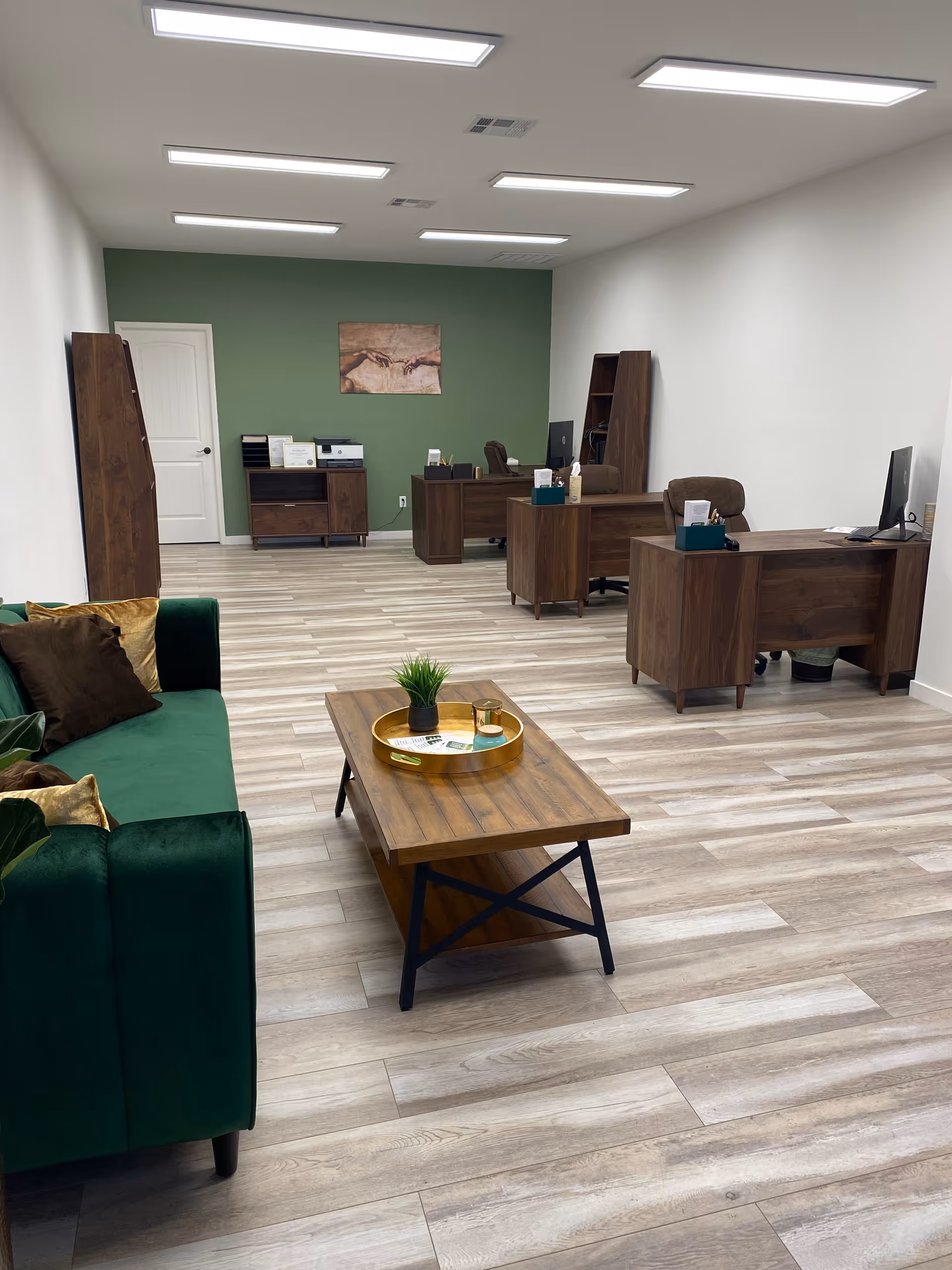 Interior of a reception area with wooden desks, green accent wall, and green sofa.
