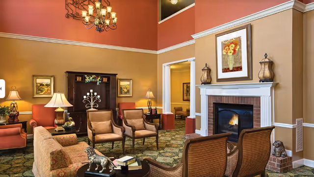 Warm, elegant common living room with seating, a fireplace, and traditional decor.