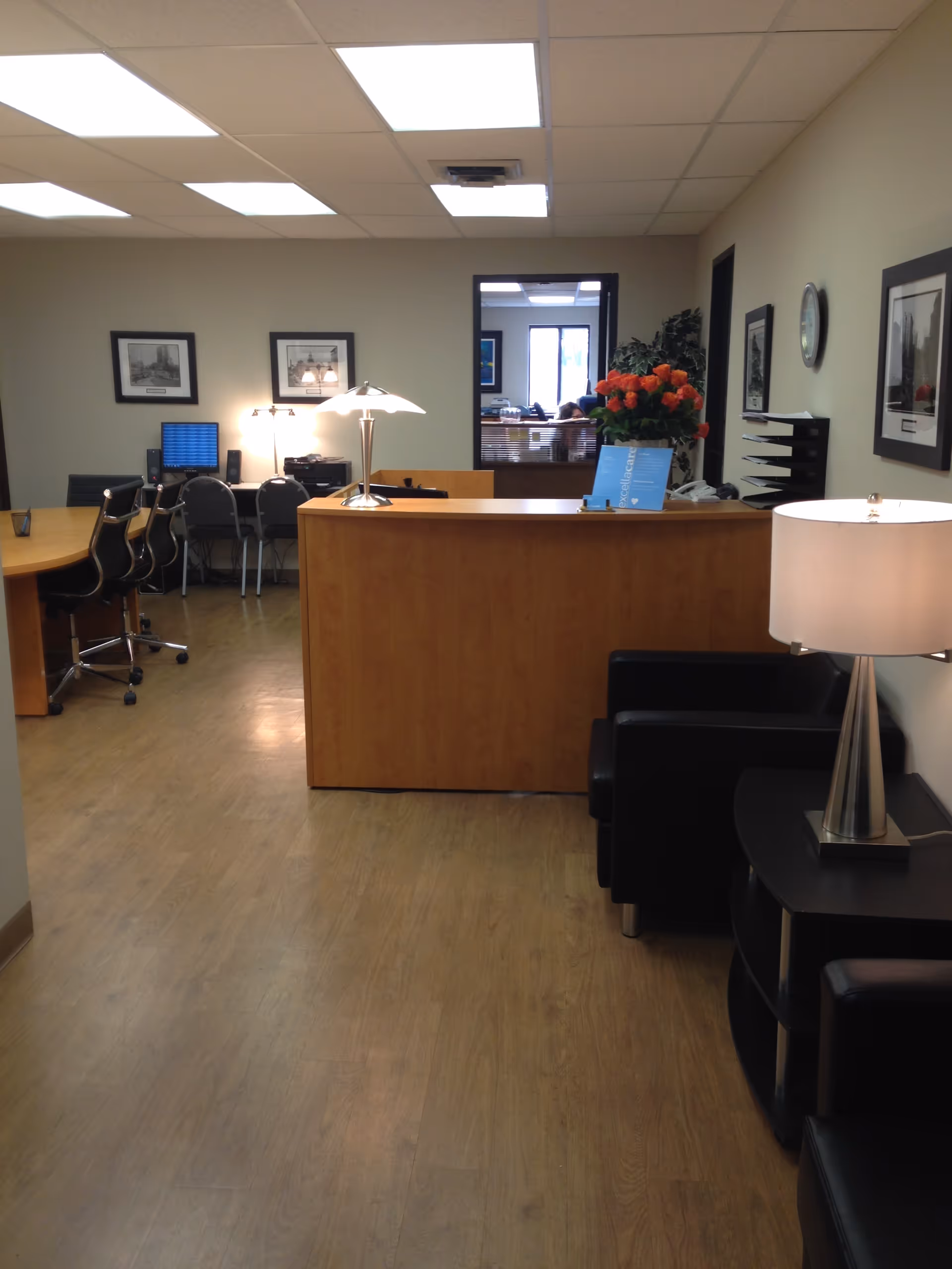 Lobby/reception area with wooden desk, seating, lamps, and wall art.