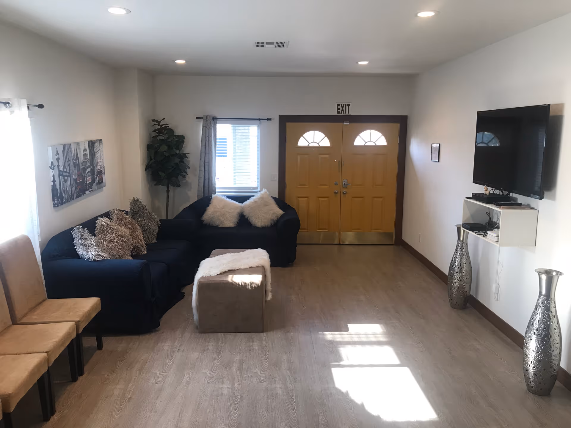 Cozy living room with navy sofas, decorative pillows, TV, and double front doors.
