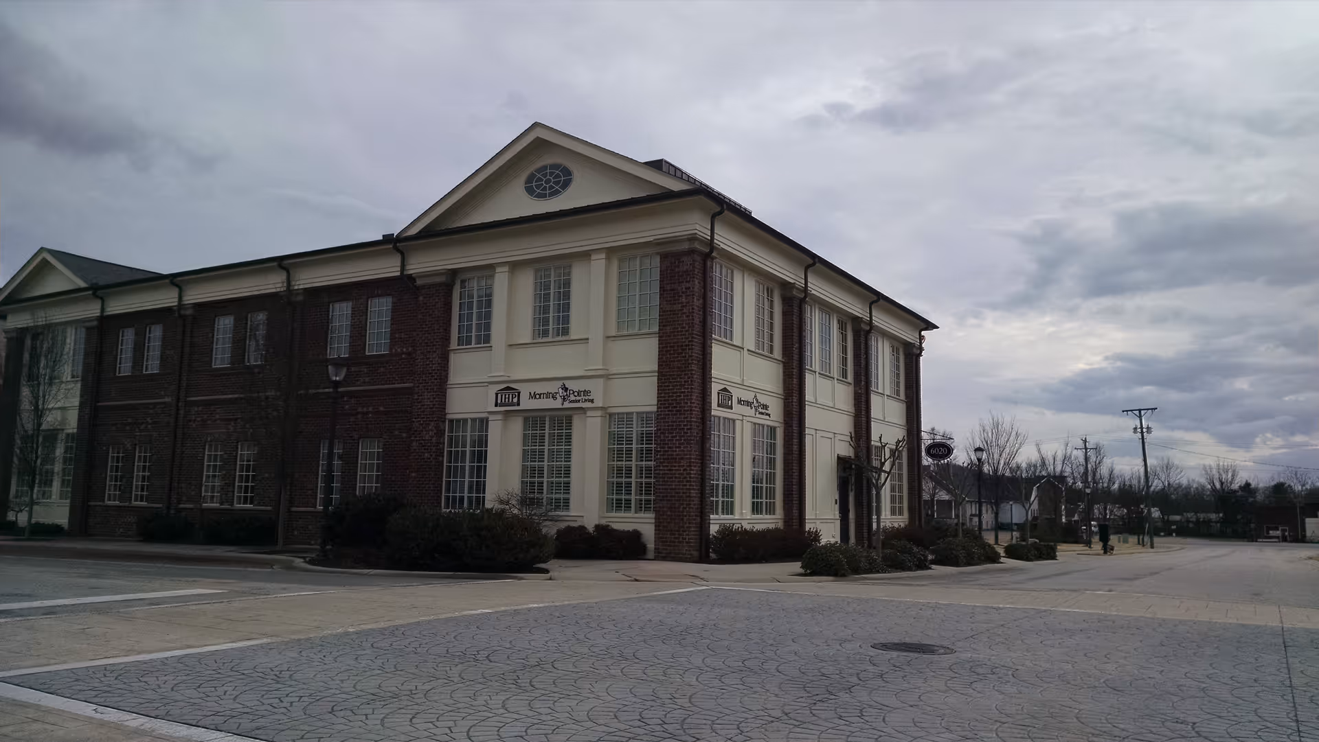 Two-story brick Morning Pointe building with beige trim, corporate signage, and surrounding parking.