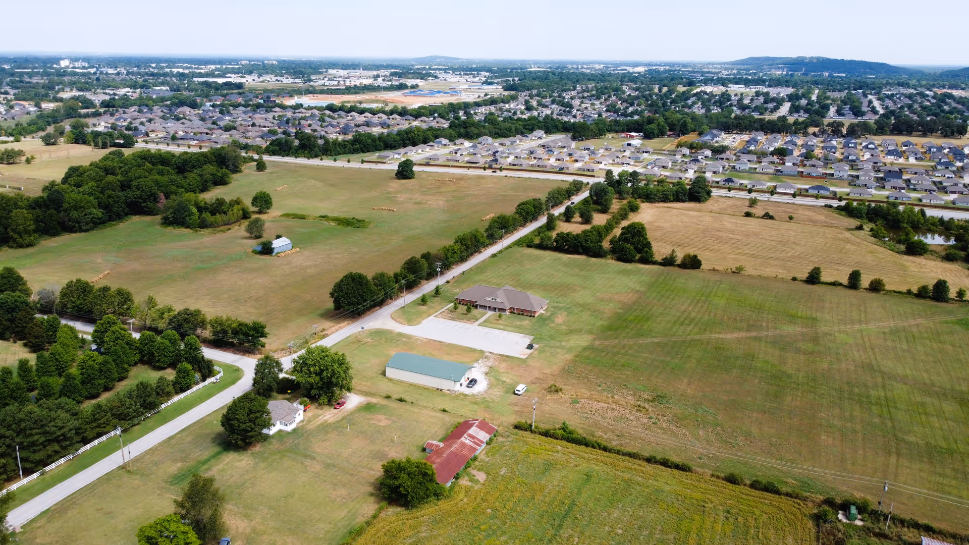 Aerial view of rural landscape with fields, roads, and scattered buildings.