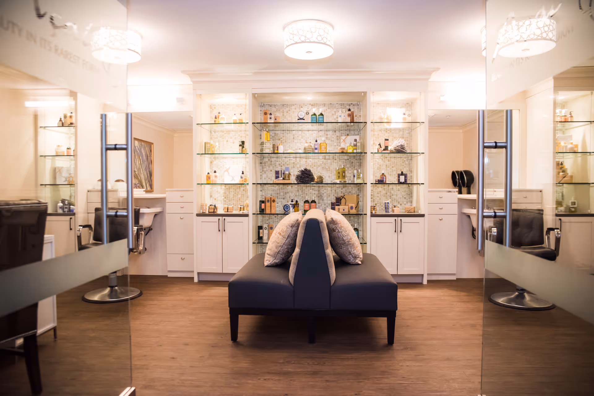 Salon-like lounge with glass display shelves and a central cushioned seating area.