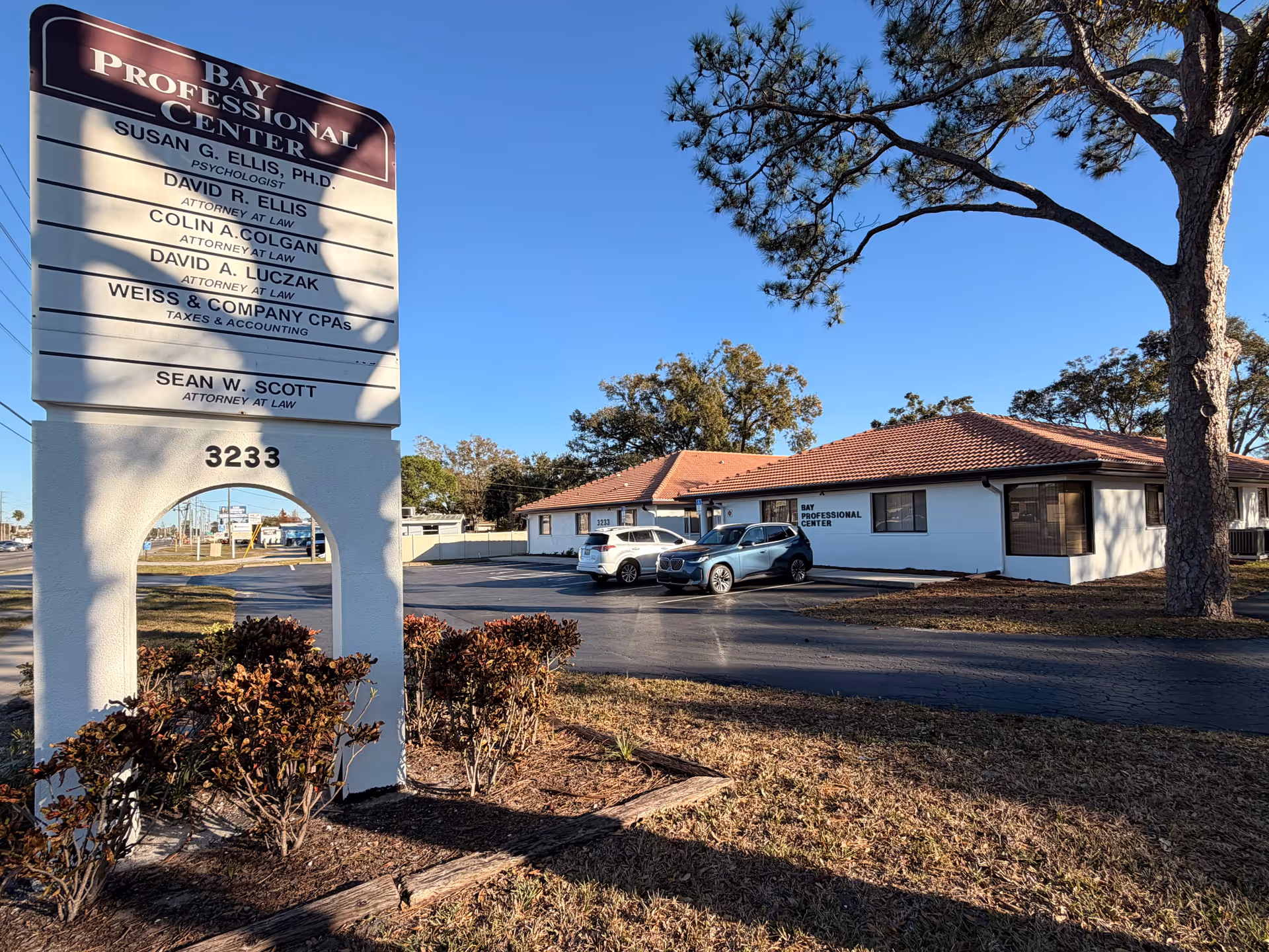 Exterior view of a white, single-story office building with a tall sign.