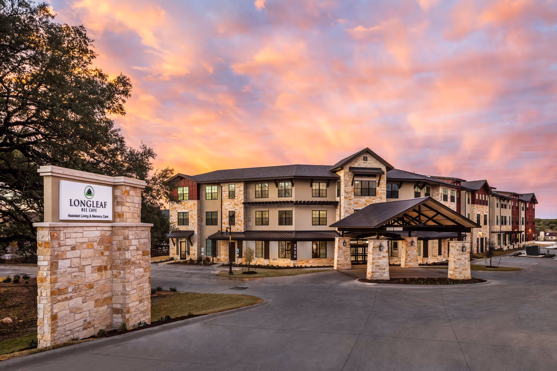 Exterior view of Longleaf Bee Cave senior living facility with a sign and driveway.