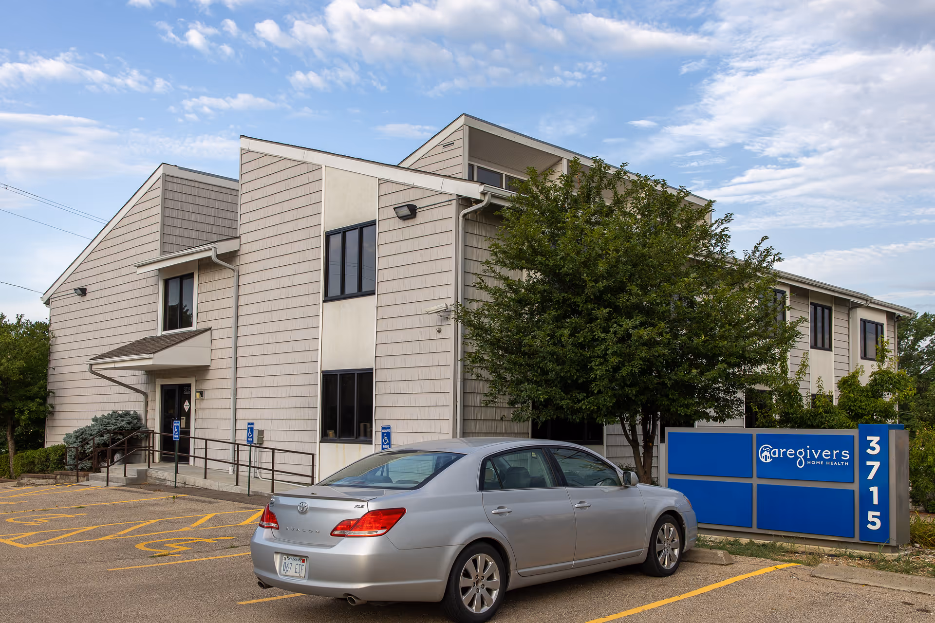 Exterior view of a Caregivers Home Health building with a blue sign and parked silver car.