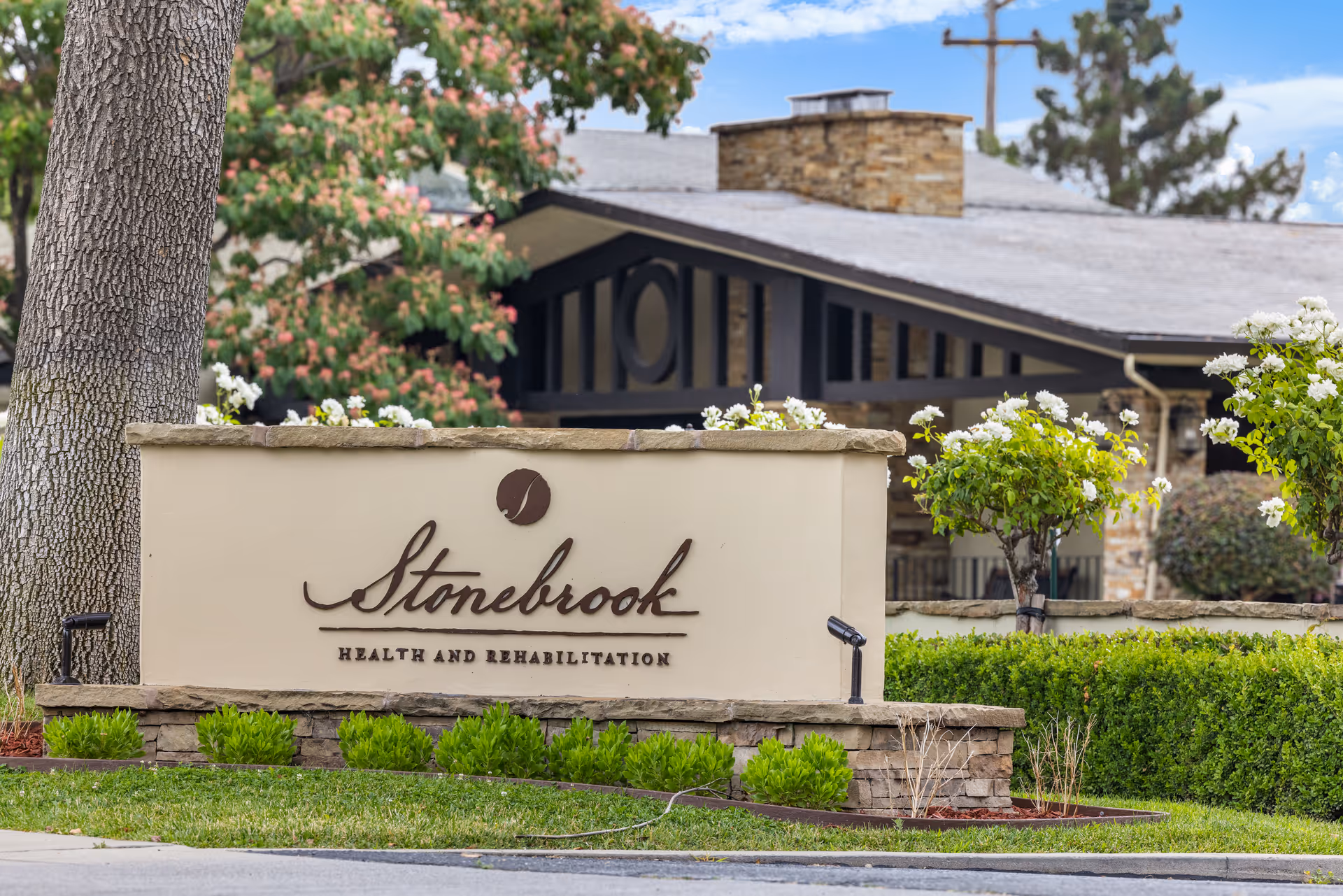 Stonebrook Health and Rehabilitation sign at landscaped entrance with building behind