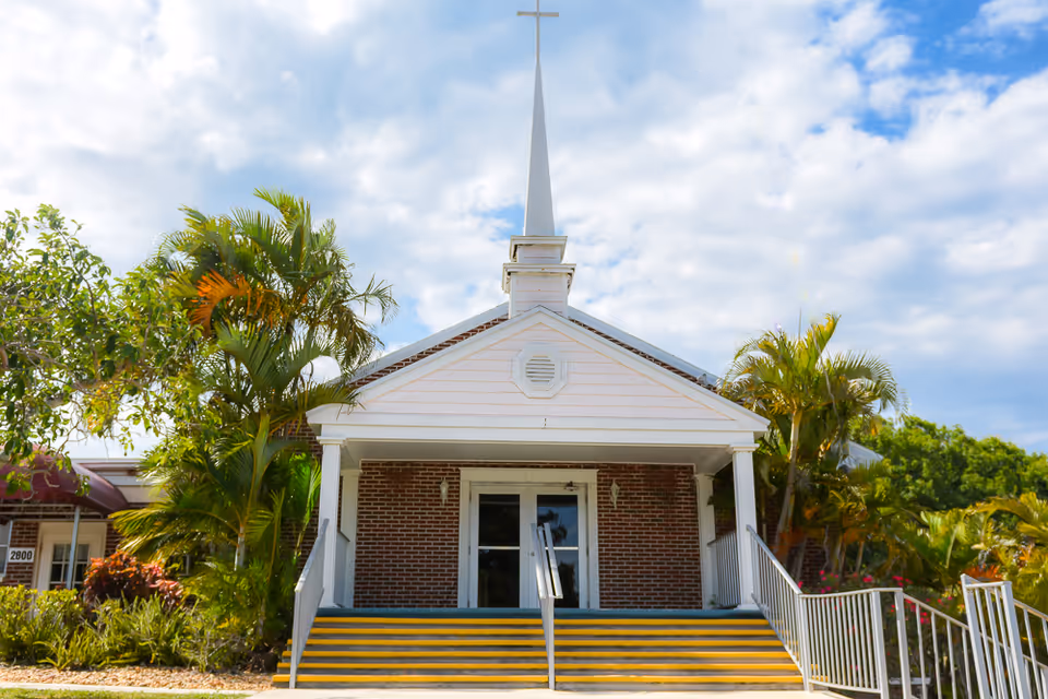 White brick building with a steeple and front steps, church-like exterior.
